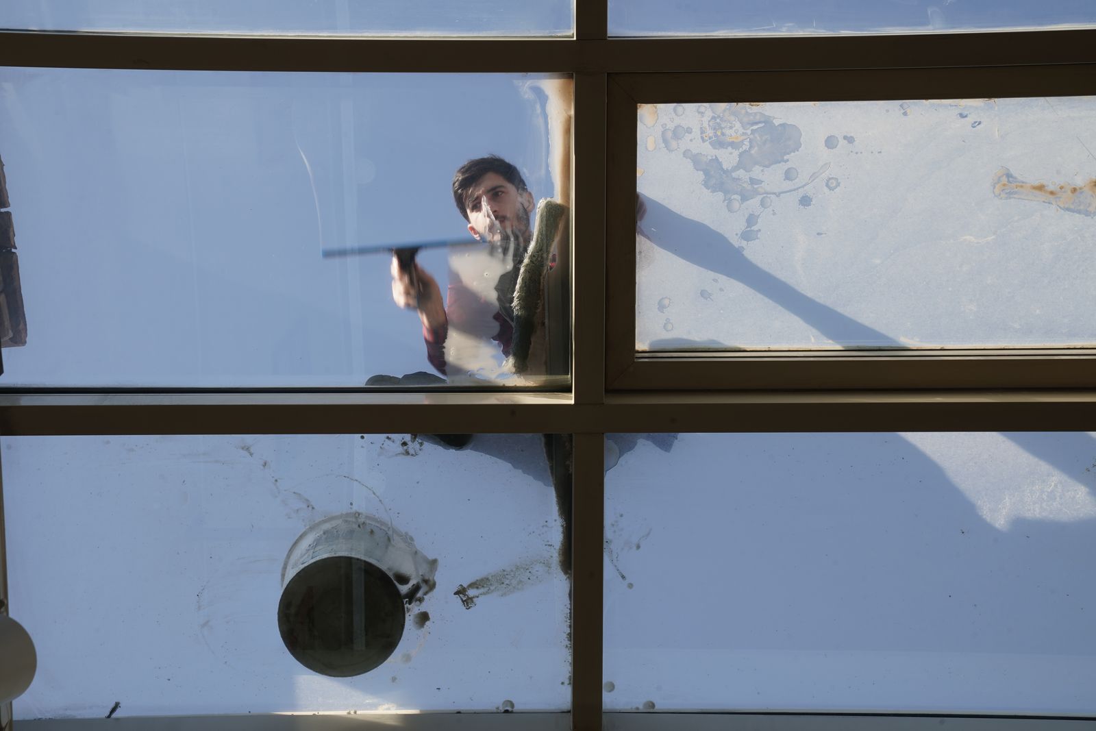 Glasreiniger säubert eine Glasfläche von außen mit dem Wischer
